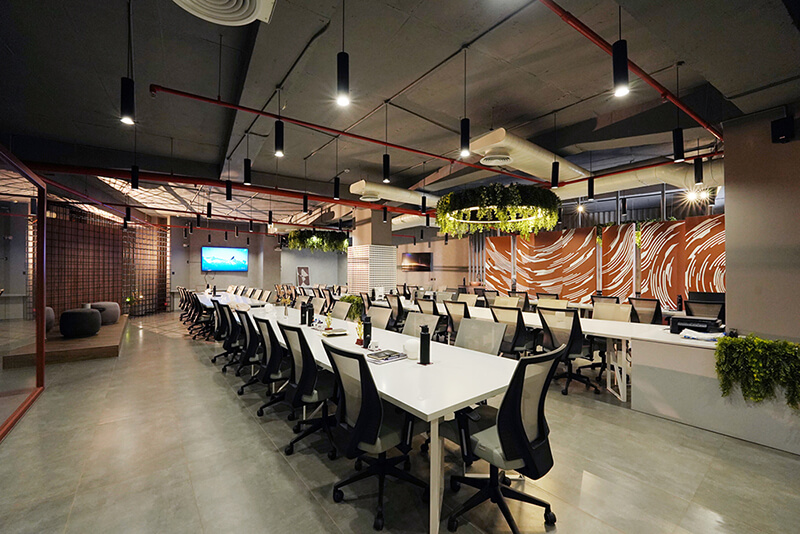 A modern office interior showcasing multiple tables and chairs positioned centrally for teamwork and meetings