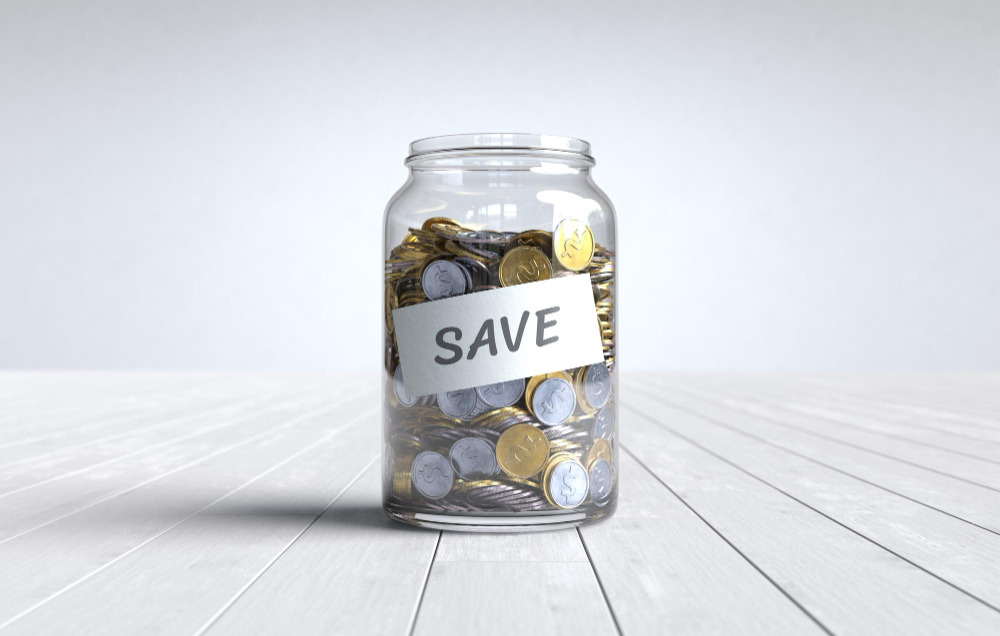 3D rendering of a savings jar with coins on a wooden table, symbolizing how to save money from your salary every month.